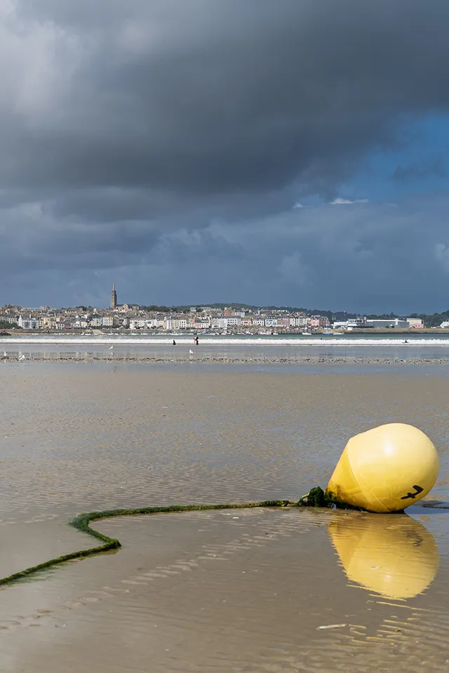 La bouée jaune repose sur le sable, marée basse à Douarnenez.