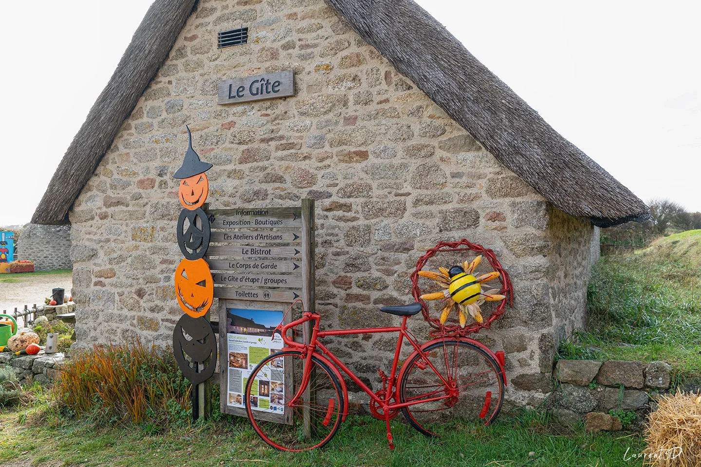 Ancien vélo rouge orné de maïs et de citrouilles devant une maison bretonne à Meneham
