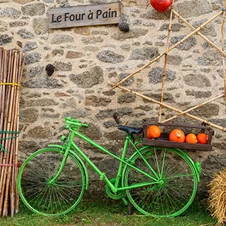 Vélo ancien peint en vert posé contre une façade en pierre du village de Meneham en Bretagne